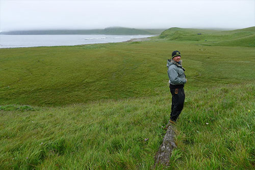 jpg A geologist stands on a drift log stranded 23 m above mean tide level, overlooking the Cabin Flat study site and Driftwood Bay, Umnak Island, Alaska.