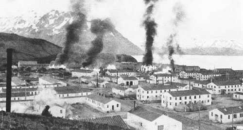 THE DUTCH HARBOR WAR Burning buildings at Ft. Mears after first enemy attack on Dutch Harbor, 3 June 1942